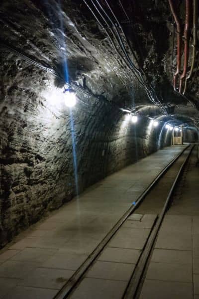 Abandoned underground mine tunnel with tracks and wiring, highlighting the hidden subsurface risks that drone surveying can miss.

