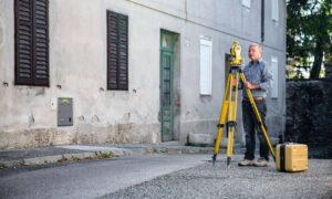Licensed land surveyor using equipment to conduct an elevation survey in a residential neighborhood