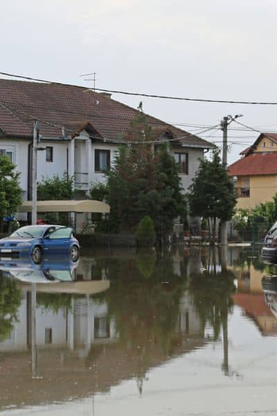 Flooded residential street with cars and homes showing the need for an elevation survey to identify flood risks
