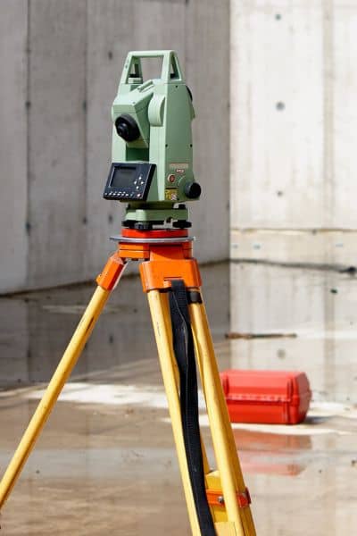 Surveying equipment measuring land elevation to plan drainage and prevent basement flooding through a topographic survey