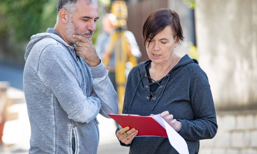 A licensed land surveyor reviewing property documents with a homeowner to clarify boundaries before issues arise