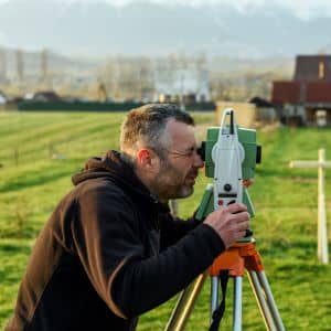 Land surveyor using measuring equipment - ALTA SURVEY Pennsylvania A licensed land surveyor using precision equipment to complete a property line survey before a home renovation