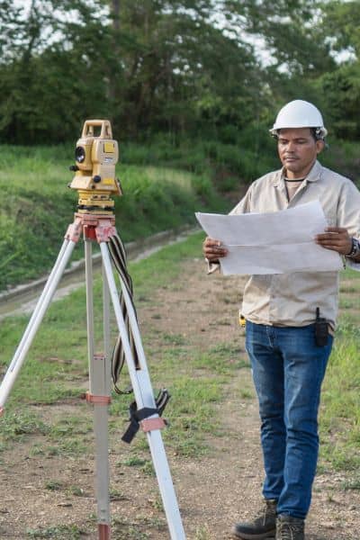 Land surveyor reviewing a site plan and checking measurements on a property