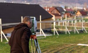 Land surveyor measuring a residential lot for a stamped site plan before construction begins