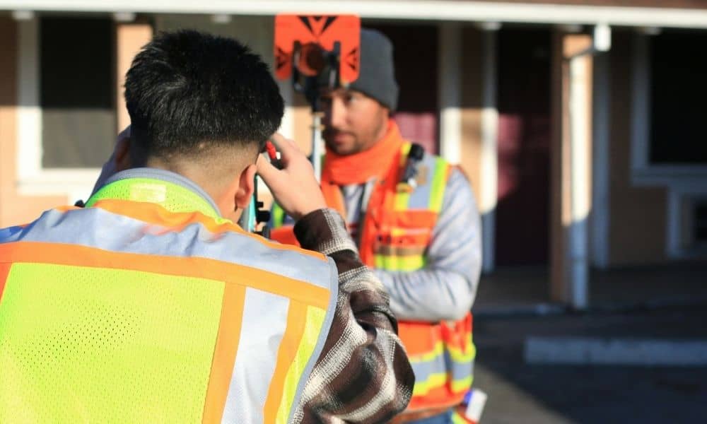 Surveyor checking property measurements with a total station during a site survey