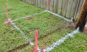 Survey markers placed beside a backyard fence to verify the property line