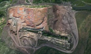 An active quarry surveyed by aerial survey drones, showing stepped benches, exposed rock faces, working floors, and haul roads