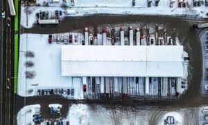 Aerial view of an industrial warehouse with loading docks, semi trailers, parking areas, and paved truck access on a property considered for an ALTA survey